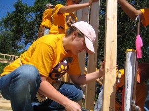 身着黄色hth华体会体育app官网衬衫的路易斯安那州立大学建筑系学生为仁爱家园建造房屋