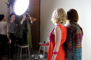 女学生用相机拍摄在明亮的工作室里穿红色衣服的女人